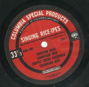 The image shows a record label with the following text:

Columbia Special Products
A Service of Columbia Records
Singing Rice-Ipes
(See printed sheet for complete Rice-Ipe instructions.)
© Riviana Foods, Inc.
Side 1
33 1/3
CSM 7901
Houston Hash
Sunnyside Rice
Cripple Creek Casserole
Texarkana Rice
Produced by Columbia Special Products
A Service of Columbia Records
© Columbia Broadcasting System, Inc.
Made in England